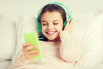 Image showing happy girl lying in bed with smartphone at home