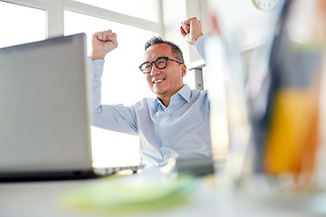 Image showing happy businessman with laptop at office