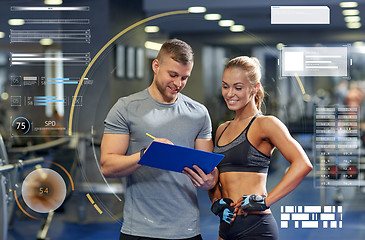 Image showing smiling young woman with personal trainer in gym