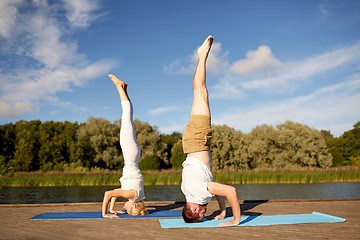 Image showing couple making yoga headstand on mat outdoors