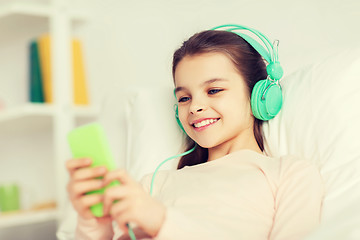 Image showing happy girl lying in bed with smartphone at home