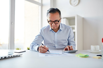 Image showing businessman with calculator and papers at office