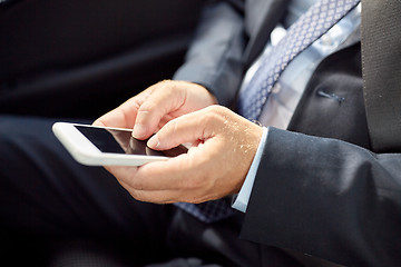 Image showing senior businessman texting on smartphone in car
