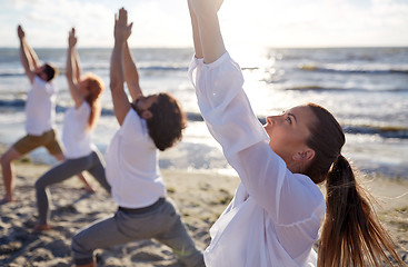 Image showing group of people making yoga exercises on beach