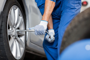 Image showing mechanic with screwdriver changing car tire