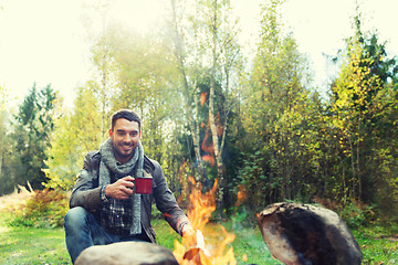 Image showing happy man drinking hot tea near camp fire