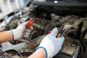 Image showing auto mechanic man with cleats charging battery