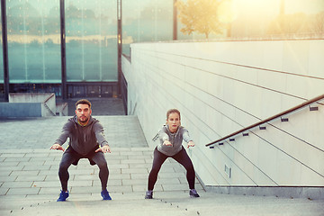 Image showing couple doing squats on city street stairs