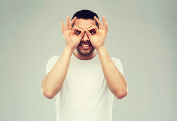 Image showing man making finger glasses over gray background