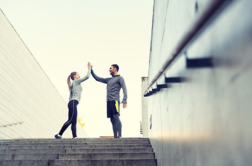 Image showing smiling couple making high five on city street