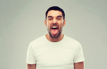 Image showing man showing his tongue over gray background