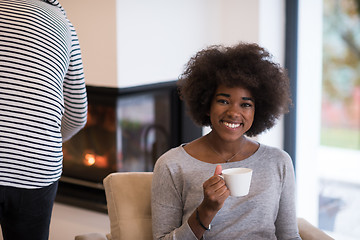 Image showing black woman drinking coffee in front of fireplace