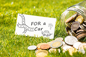 Image showing The coins at glass jar for money on green grass