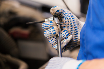 Image showing mechanic man with wrench repairing car at workshop