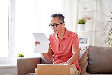 Image showing man with parcel box reading invoice at home