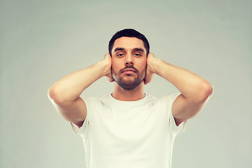 Image showing latin man covering his ears with hand palms