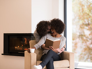 Image showing multiethnic couple hugging in front of fireplace