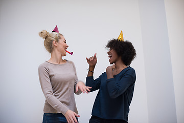 Image showing smiling women in party caps blowing to whistles