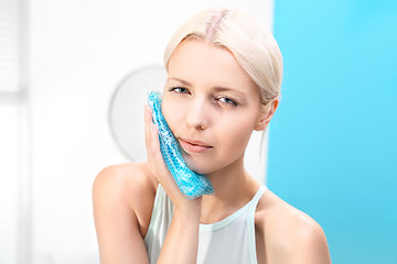 Image showing Help toothache. Wrap and cure The woman puts a cold compress useful for toothache. 