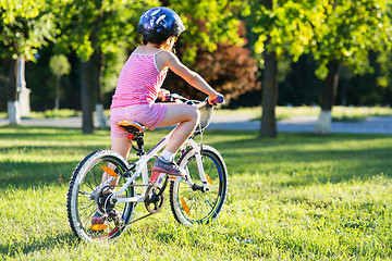 Image showing happy child girl riding bicycle in summer sunset