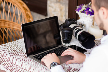 Image showing happy young man working on laptop outdoors