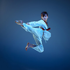 Image showing Young boy training karate on blue background