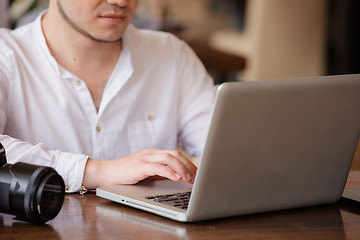 Image showing photographer with the camera works on his laptop