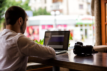 Image showing photographer with the camera works on his laptop