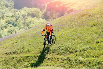 Image showing Young man traveler riding on bicycle with red backpack