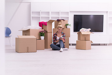 Image showing woman with many cardboard boxes sitting on floor