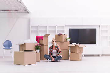 Image showing woman with many cardboard boxes sitting on floor