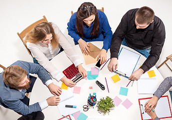 Image showing Team sitting behind desk, checking reports, talking. Top View