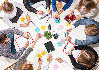 Image showing Team sitting behind desk, checking reports, talking. Top View