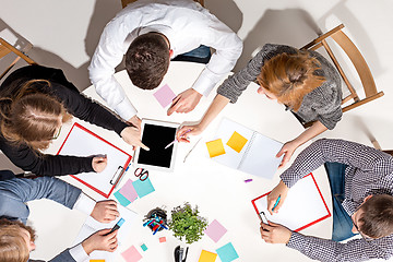 Image showing Team sitting behind desk, checking reports, talking. Top View