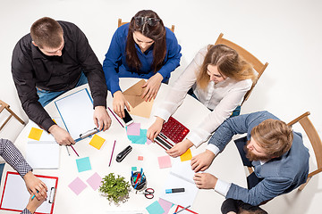 Image showing Team sitting behind desk, checking reports, talking. Top View