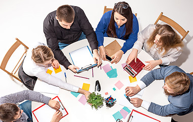 Image showing Team sitting behind desk, checking reports, talking. Top View