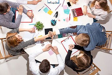 Image showing Team sitting behind desk, checking reports, talking. Top View