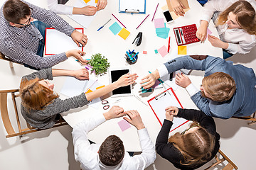 Image showing Team sitting behind desk, checking reports, talking. Top View