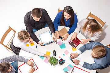 Image showing Team sitting behind desk, checking reports, talking. Top View