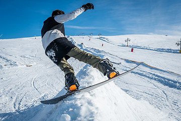 Image showing Snowboarder sliding against blue sky