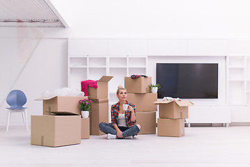 Image showing woman with many cardboard boxes sitting on floor