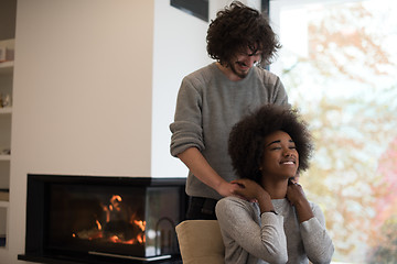 Image showing multiethnic couple hugging in front of fireplace