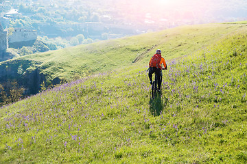 Image showing Young man traveler riding on bicycle with red backpack