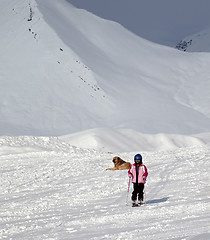 Image showing Little skier on ski slope at sun winter day and gray sky before 