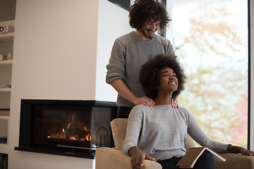 Image showing multiethnic couple hugging in front of fireplace