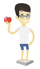 Image showing Man standing on scale and holding apple in hand.