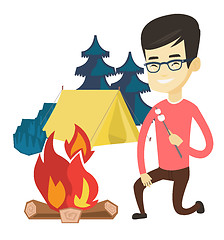 Image showing Young man roasting marshmallow over campfire.