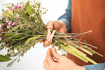 Image showing Florist at work: the female hands of woman making fashion modern bouquet of different flowers