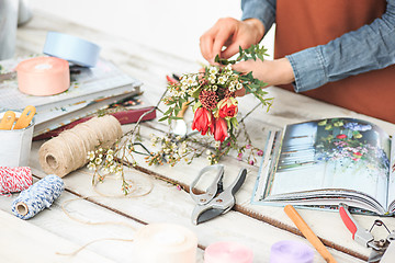 Image showing Florist at work: the female hands of woman making fashion modern bouquet of different flowers