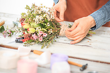 Image showing Florist at work: the female hands of woman making fashion modern bouquet of different flowers